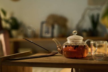 Boş bardak, şeffaf çaydanlık, sıcak bitkisel çay ve ahşap tutacağı, tüten aromalı sopa.