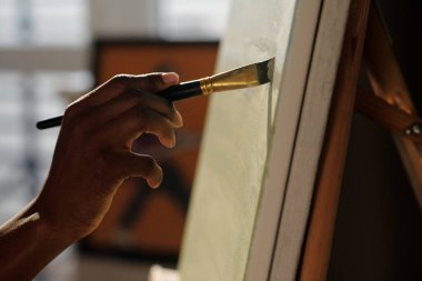 Bir sanat stüdyosundaki tuvale ustalıkla resim yapmak, çevreye yumuşak bir şekilde odaklanmak, fırça darbeleriyle güzel bir sanat eseri yaratmak.