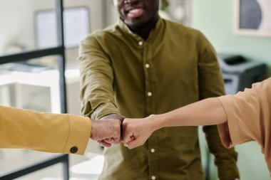 Modern ofis ortamında birbirini el sıkışarak selamlayan bir grup meslektaşı, olumlu takım çalışması ve işbirliği sergiliyor