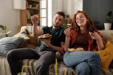 Hamburgerci genç adam ve patates kızartması ve uzaktan kumandalı kız arkadaşı ev sinemasında ilginç bir film izliyorlar.