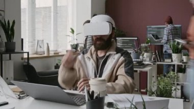 AR kulaklıklı genç Orta Doğulu erkek geliştiricinin tam zamanlı döngüsü. Rutin iş günlerinde yoğun IT başlangıç ofisinde sanal gerçeklik projesi üzerinde çalışıyor, kod yazıyor ve test ediyor.