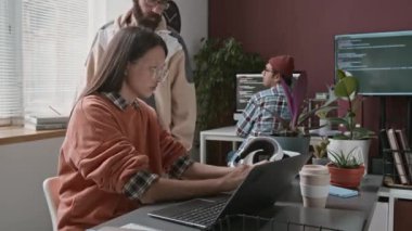 BT şirketinde acil bir proje üzerinde çalışan, dizüstü bilgisayara, tablete kod yazan, deftere algoritma yazan, kahve içen, stresli, çift ırklı genç bir kadın programcının orta boy zaman çekimi.