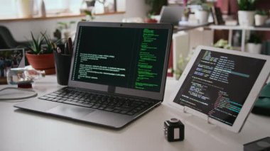 IT şirketinin ofisindeki programcı masasına kimse yaklaşmıyor - dizüstü bilgisayar kodlu tablet siyah ekran, saksı bitkileri ve kişisel eşyalar üzerinde çalışıyor