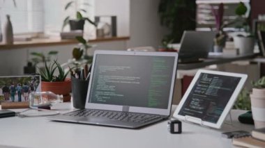 IT başlangıcının ofisindeki yazılım geliştiricisinin masasına kimse yaklaşamaz - dizüstü bilgisayar kodlu tablet siyah ekran, kişisel eşyalar ve çerçeveli fotoğraf üzerinde çalıştırılır