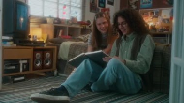 Beyaz tenli öğrencilerin yatakta oturup kitap okudukları, içeriği tartıştıkları, birlikte ders çalıştıkları, dekoratif yatak odasında, nostaljik 90 'larda,