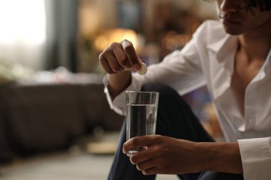 İçki yüzünden akşamdan kalma haldeyken bardağa coşkulu haplar koyan tanınmayan bir adamın kesikli çekimi.