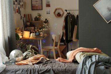 Kirli çarşaflı, battaniyeli, elbiseli, disko toplu, boş şişeli ve plastik bardaklı çift kişilik yatak.