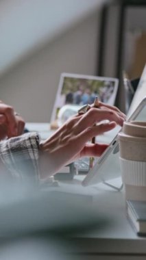 Şirket ofisindeki masada tablet ve dizüstü bilgisayar üzerinde çalışan tanınmayan genç kadın programcının elleri dikey olarak birbirine yakın.