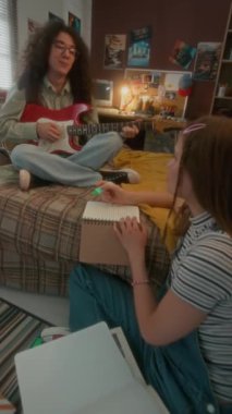 Yatakta kız arkadaşı için gitar çalan, ev ödevi yapan ve erkek arkadaşıyla konuşan, okuldan sonra geceyi birlikte geçiren, 90 'lı yaşlarda neşeli, kabarık saçlı bir adamın el kamerası görüntüsü.