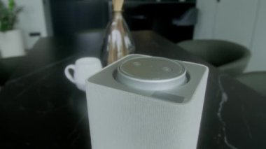 Minimalist modern aile evinin mutfak veya yemek odasındaki siyah mermer masa üzerinde sanal asistanı olan beyaz yerli akıllı konuşmacıya kimse yakın çekim yapmaz.
