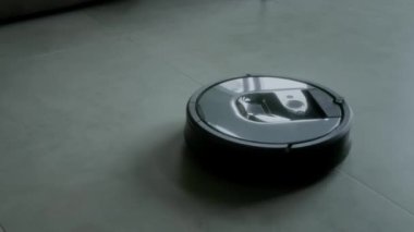 Hiç kimse robot elektrikli süpürgenin yakın çekim görüntüsü almaz. Gri taşlı zeminde hareket eder, modern akıllı evdeki tozları temizler ve toplar.