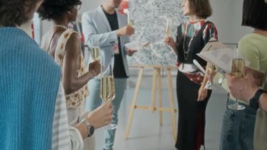 Sanat galerisinde sergi açılışına katılırken şampanya kadehleriyle tanınmayan çeşitli konukların orta boy arka çekimi, kadın sanatçının yeni başyapıt hakkında konuşmasını dinlemek,