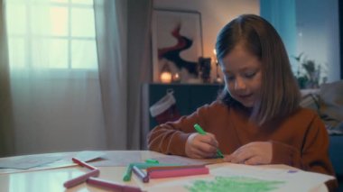 Kahverengi sweatshirt 'lü küçük mutlu beyaz kızın göğüs kafesi fotoğrafı. Akrabalarına ya da Noel Baba' ya yazdığı mektup. Noel Baba 'nın süslenmiş evinde, tatil beklentisi, büyülü bir an.