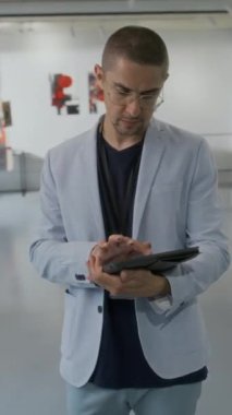 Modern sanat sergisi açılışında kendine güvenen beyaz erkek sanat müzesi müdürünün orta boy dikey portresi ya da gri takım elbiseli ve gözlüklü yönetici kameraya bakıyor.