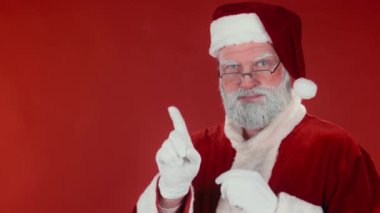 Gözlüklü, geleneksel kırmızı kostümlü, kameraya bakıp parmağını sallayan, tatminsizliğini, şablonunu ya da kopyalayıcısını gösteren sıkı Noel Baba 'nın göğsünden çekilen fotoğrafı.