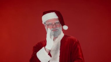 Neşeli, enerjik bir Noel Baba 'nın göğsüne bıçak darbesi. Kameraya bakıp dans ediyor, el sallıyor ve modern dans hareketleri yapıyor. Kırmızı arka plan, şablon ya da kopyalama alanı karşısında eğleniyor.