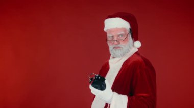 Meşgul beyaz Noel Baba 'nın göğsünden bıçaklanarak çekilmiş fotoğrafı çalar saati gösteriyor ve kırmızı arka planı olan iyi çocuklara hediyeler dağıtmak için acele ediyor. Şablon için uygun, alanı kopyala