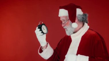 Kırmızı arka planda ciddi bir Noel Baba 'nın göğüs portresi var. Alarm saatine bakıyor. Noel' i kutlamak için tam zamanı. Şablon ve kopyalama alanı için uygun