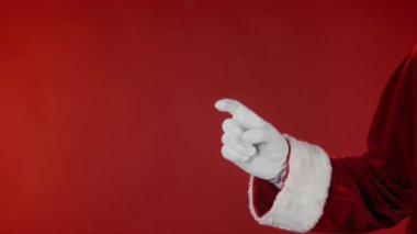 Geleneksel kostümlü tanınmayan Noel Baba 'nın kırmızı arkaplandaki fotokopi alanını gösteren ve onaylanmış, tavsiye edilen ve reklamını yapan bir fotoğraf. Şablon için uygun