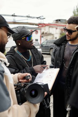 Bir grup insan ellerinde belge ve kamerayla proje tartışması yapıyor. Kentsel zemin ve günlük giysi işbirlikçi ve yaratıcı ortam