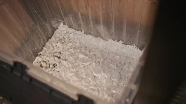 Hiç kimse geri dönüşüm fabrikasında makine öğütme işlemi sırasında şeffaf tepsiye düşen parçalanmış beyaz plastik plastik parçacıkları çekmez.