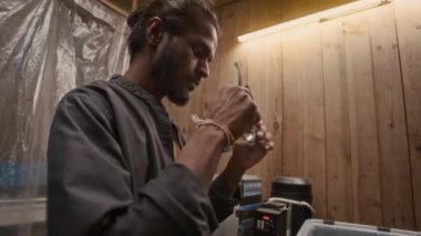 Asyalı erkek plastik geri dönüşüm atölyesi çalışanı polietilen şişe kapaklarını öğütücüye atmadan önce koruyucu gözlük takıyor.