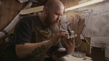 Plastik ekstrüzyon için yeni yapılmış metal kalıpları kontrol eden önlüklü, kaslı kel beyaz erkek geri dönüşüm atölyesi sahibinin orta boy yakın çekimi, pürüzsüzlük için parmağı ile iz sürme şekli