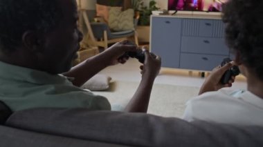 Black father 'ın küçük oğluyla TV' de video oyunu oynarken, joystickleri kullanırken, evde, ailede ve bağ kurarken birbirlerini engellerken.