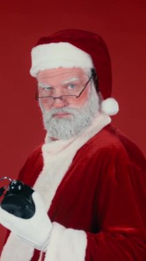 Kafkasyalı Noel Baba 'nın dikey göğsünden bıçaklama görüntüsü alarm saatini gösteriyor ve kırmızı arka planı olan iyi çocuklara hediyeler dağıtmak için acele ediyor. Şablon, boşluğu kopyala