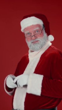 Noel Baba 'nın dikey portresi kostümlü müşterilere ürününüzü öneriyor, kırmızı arka planda iyi niyet göstergesi. Şablon için uygun, alanı kopyala