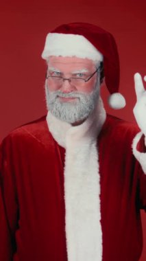 Noel 'in başlangıcını kutlayan neşeli Noel Baba' nın dikey bıçaklama portresi, parti topu patlatma, kırmızı arka planda her yerden konfeti düşmesi. Şablon, boşluğu kopyala