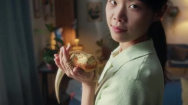 Genç Çinli kızın orta boy portresi. Evinin penceresinin önünde duruyor. Elinde kızıl sakallı kertenkele, kameraya bakıyor ve neşe ve mutlulukla gülümsüyor.