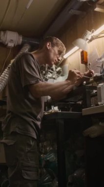 Beyaz adamın garajda ya da atölyede torna keserken, tornavida ve ingiliz anahtarı ile cıvataları sıkarken orta boy düşey düşük açılı çekimi.