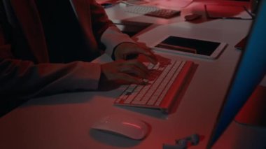 Güvenlik duvarı ihlali sırasında veya şirket sistemine saldırı sırasında klavyeye kırmızı ışık yakarak yazı yazan Kafkasyalı kadın bilişim güvenlik uzmanının ellerini ve yüzünü eğik tutmak