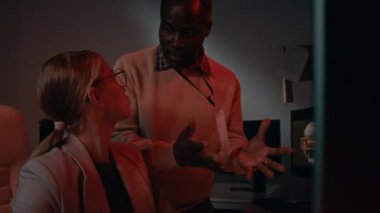 Panikleyen beyaz kadın sistem yöneticisi ve Afrikalı Amerikalı erkek yöneticinin bilgisayar korsanlığı saldırısında sistem arızasını tartışırken bağırıp tartışırken görüntüsü.