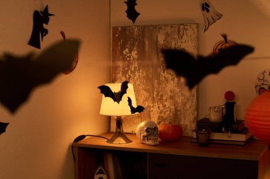 Lamba, soyut resim, insan kafatası, kitaplar, balkabağı ve mumlarla loş bir evin köşesinde.