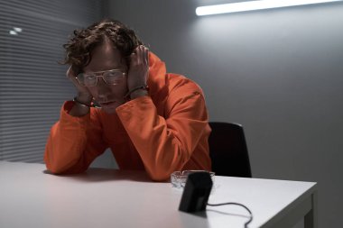 Panjurları ve yapay ışığı olan bir odada masada otururken derin düşüncelere dalmış bir adamın yüzü üzerine uzanan portresi. Düşünceli ifade ve sıradan poz