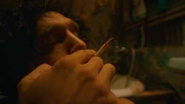 Akşamları banyoda tek başına oturmuş anlamsız ve ümitsiz bir geleceği düşünerek yavaşça nefes alıp veren zayıf sakallı, beyaz bir adamın yan görüntüsü.