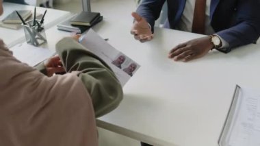 Siyahi, takım elbiseli ve gözlüklü bir konsolosluk görevlisinin, elçilikteki görüşme sırasında Müslüman başvuru formunu kontrol ederken çekilmiş bir fotoğrafı.