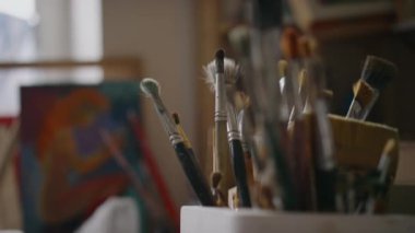 Dağınık, küçük sanat stüdyosundaki boya fırçalarına hiç kimse yaklaşamaz. Gün ışığında, bulanık, bitmemiş bir resmin önünde.