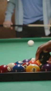 Piramitte bilardo toplarını parçalayan ve kulüpte bilardo topuyla onları kıran isimsiz arkadaşların dikey yakın çekimi.