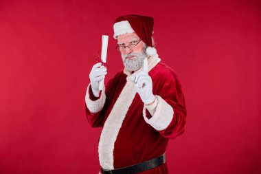 Noel Baba 'nın portresi geleneksel kıyafetler giyiyor, tomarı tutuyor ve kameraya bakıyor, bayram ruhunu ve festival temasını vurguluyor.