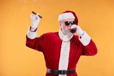 Noel Baba geleneksel kırmızı takım elbise giyip güneş gözlüğü takarken puro ve içkinin tadını çıkarıyor ve rahat bir tavır sergiliyor. Arka plan sağlam bir renktir, neşeli bir hava verir.