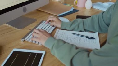 Ofiste masa başında oturan, bilgisayar klavyesinde yazan, yazılım kodları yazan, sonra da deftere algoritma çizen tanınmayan kadın programcıların orta derecede yakın çekimleri.