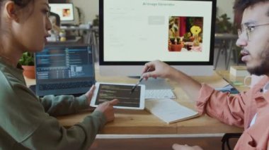 Genç Çinli kadın ve Orta Doğulu erkek yazılım geliştiricilerin tablet ekranda bilgisayar kodu üzerinde tartışırken yenilikçi yapay zeka projesi üzerinde çalışırken orta boy çekimleri.