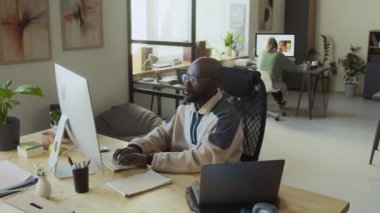 Bilgisayar şirketinde çalışan, yazılımları test eden, başarılı bir koşuda sevinçle tezahürat yapan ve yumruklarını sallayan meşgul genç siyahi erkek programcının orta ölçekli görüntüsü.