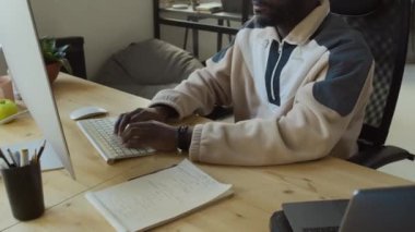 IT 'nin başlangıç ofisinde çalışan genç Afrikalı Amerikalı erkek yazılım geliştiricisinin orta ölçekli yakın çekimi. Program kodunu çalıştırmak, başarılı bir testte sevinçle bağırmak ve yumruk sallamak.
