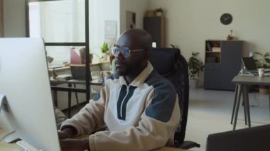 Orta boy bir Afro-Amerikan erkek programcı. Günlük eşofmanlarıyla bilgisayar başında oturuyor. Sonra esniyor, sırtı ve kol kaslarını esnetiyor.