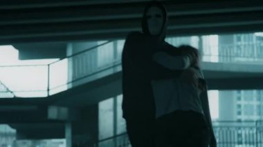 Siyah kapüşonlu ve maskeli kimliği belirsiz bir suçlunun el kamerası görüntüsü. Genç bir kadını sakinleştiriyor ve onu omuzlarına alıyor. Bilinçsiz kurbanı ıssız bir yere götürüyor.