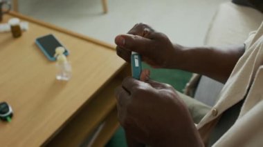 Afro-Amerikalı adamın evde diyabet tedavisi sırasında insülin kalemini iğneye hazırlarken omzunun üstünden yaklaş.